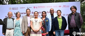 Ocho personas, cuatro hombres y cuatro mujeres, posan frente a un banner blanco con logotipos y texto. Al fondo se ven árboles y el logo de INAH