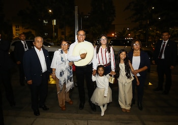 Roberto Sánchez sonríe mientras camina con su familia, incluyendo dos niñas pequeñas, dos mujeres y un hombre mayor, en la noche