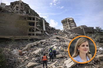Edificios derrumbados y escombros. Cuatro personas con uniformes de rescate. Círculo naranja que muestra a una mujer rubia con collar de perlas, hablando por micrófono.