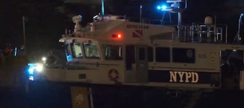 Un barco policial del NYPD con luces azules y rojas encendidas en la oscuridad de la noche, se observa el número 628 y la inscripción Scuba Team