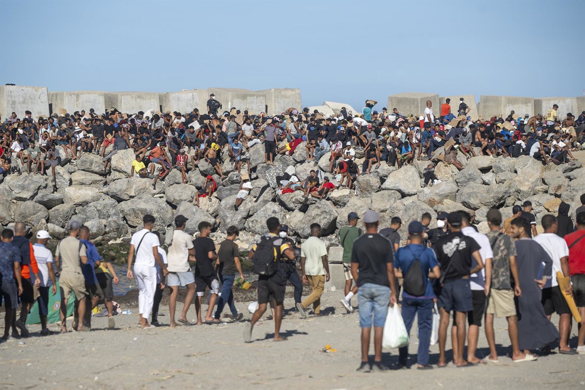 Miembros de la Cruz Roja reparten comida a los inmigrantes en una playa, a 21 de agosto de 2026, en Ceuta (España). (Marcos Moreno/Europa Press)