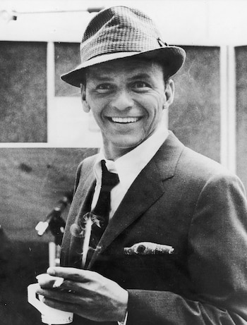 El cantante y actor estadounidense Frank Sinatra sonríe mientras sostiene un cigarrillo y una taza de café en un estudio de grabación, en los años cincuenta (Hulton Archive/Getty Images)