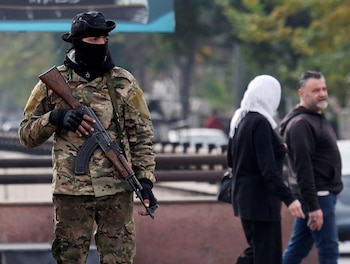Varias personas pasan junto a un combatiente rebelde que monta guardia en la plaza Abbasiyyin en Damasco Dic 11, 2024. REUTERS/Amr Abdallah Dalsh