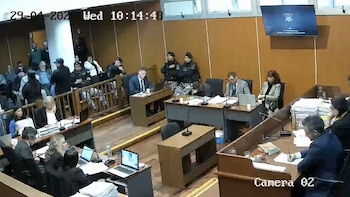 Interior de una sala de juicio con varias personas sentadas en mesas y bancos. Se observan abogados, personal de seguridad y público