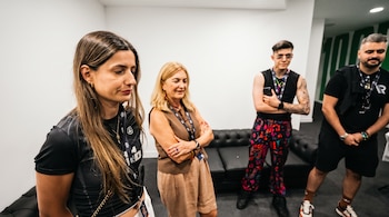 Cuatro personas, dos mujeres y dos hombres, de pie en una sala. Llevan pases de identificación. Hay un sofá negro y una pared verde en el fondo.