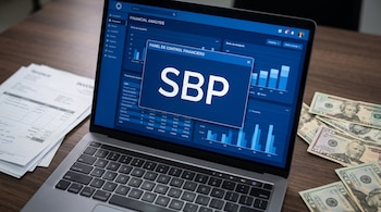 Una computadora portátil muestra la sigla SBP en pantalla, colocada en una mesa de madera junto a billetes de dólares y facturas de papel.