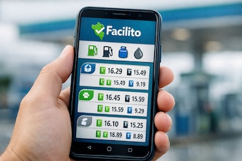 Mano sosteniendo un teléfono inteligente, pantalla con la aplicación Facilito mostrando el logo de Perú, íconos y precios de combustibles, fondo de estación de servicio borroso.