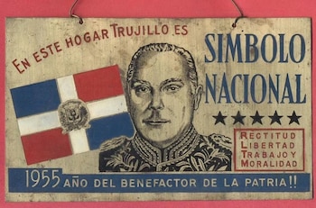Un cartel que debía colgarse en todos los hogares dominicanos durante el Trujillato. Decía: «En esta casa Trujillo es un símbolo nacional». «Rectitud. Libertad. Trabajo. Moralidad». «1955: Año del Benefactor de la Patria». (Imagen retomada de The Atlantic)