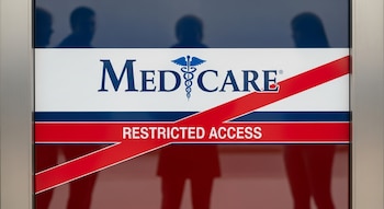 Plano cerrado de una puerta de vidrio con el logo de Medicare cruzado por una banda roja que dice 'Acceso Restringido'; reflejos de personas difusas detrás.