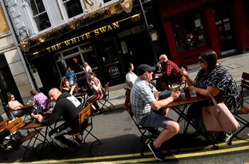 Consumidores beben en mesas al aire libre en Londres (Reuters)