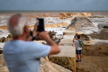 Dos personas hacen fotografías al oleaje este domingo en la playa de Vinaros (Castellón).EFE