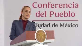 Claudia Sheinbaum habla detrás de un podio con el escudo de México ante un panel con la frase Conferencia del Pueblo.
