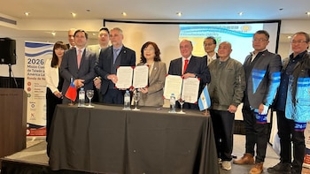 Un grupo de personas viste trajes y exhibe carpetas con documentos frente a las banderas de Taiwán y Argentina