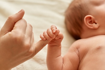 Un bebé sujeta la mano de su madre (Magnific)