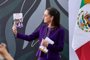 Claudia Sheinbaum sostiene un folleto sobre orientación para jóvenes en una sala con la bandera de México