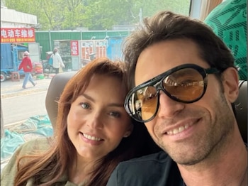 Selfie de Angelique Boyer y Sebastián Rulli sonriendo, con ella a la izquierda y él a la derecha usando gafas de sol, dentro de un vehículo
