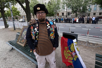 Un hombre identificado por medios polacos como Robert Kuzovkov y por la fiscalía como Robert K., de acuerdo con las leyes polacas de privacidad, que según dijeron era un artista con el pseudónimo Semyon Skrepetsky, posa para una foto con una de sus obras junto a la embajada rusa en Berlín, Alemania, el viernes 12 de junio de 2026, cuatro días antes de morir baleado en Biala Podlaska, Polonia, según autoridades polacas. (Vasily Krestyaninov/SOTA via AP)