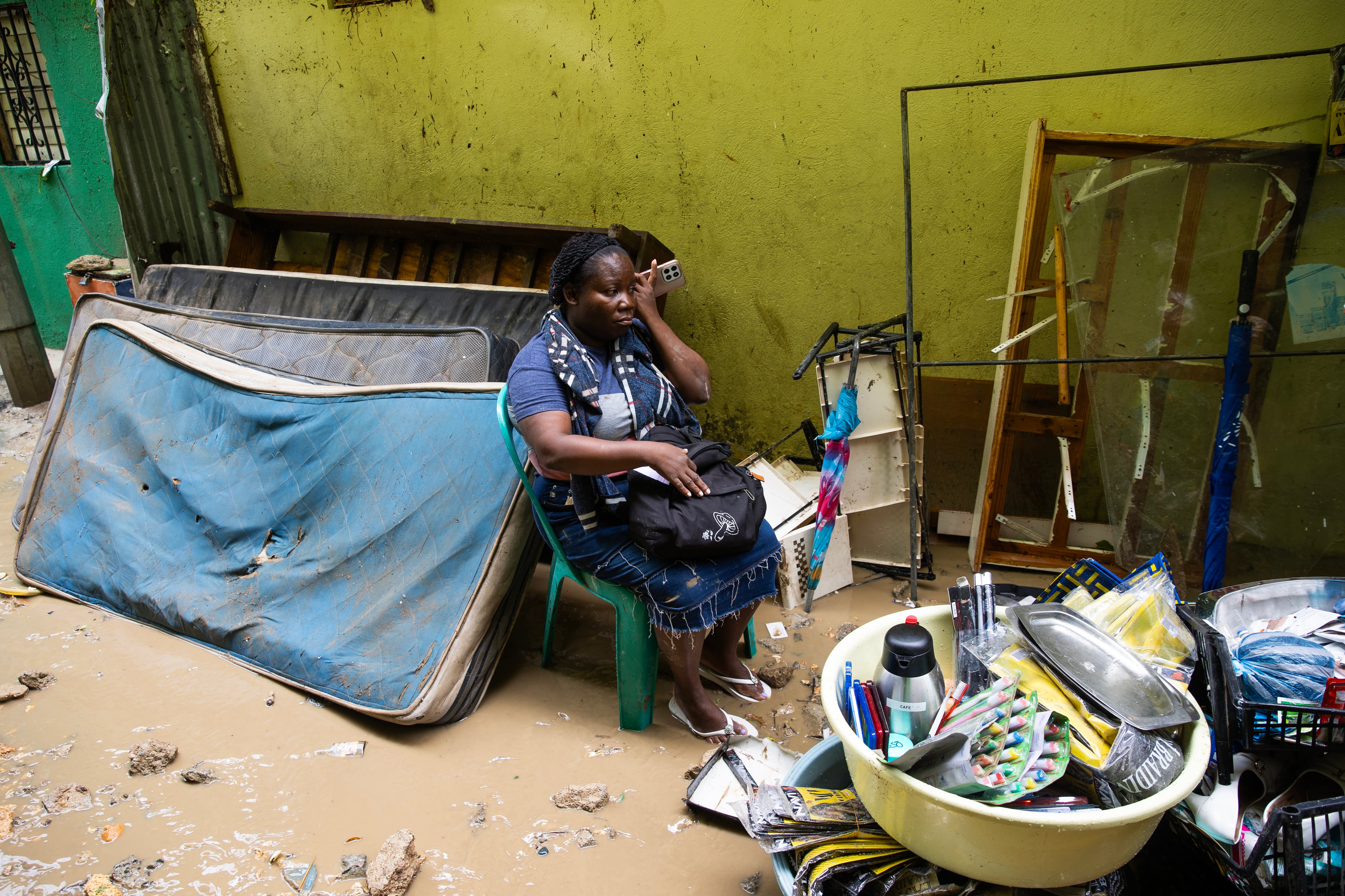 SANTO DOMINGO (REPÚBLICA DOMINICANA), 08/04/2026.- Una mujer sostiene un teléfono frente a sus pertenencias este miércoles, en Las 800, un barrio humilde en Santo Domingo (República Dominicana), que ha sufrido graves inundaciones a causa de las torrenciales lluvias arrojadas por una vaguada que incide sobre gran parte del país. EFE/Orlando Barría