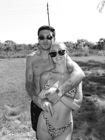 Fotografía en blanco y negro de un hombre y una mujer con gafas de sol y traje de baño abrazados en un entorno natural