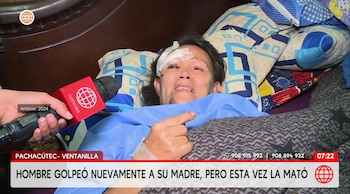 Una mujer con vendaje en la ceja derecha y un hematoma en el ojo yace en una cama mientras habla frente a un micrófono de televisión
