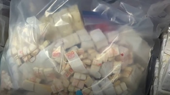 Primer plano de una bolsa de plástico transparente llena de múltiples fardos pequeños de billetes de efectivo de color claro