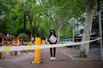FOTO DE ARCHIVO. Una mujer extranjera con agua embotellada camina por una calle durante el confinamiento de abril en Shanghái (Reuters)