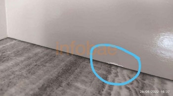 Primer plano de un salto de pintura en la parte inferior de una superficie blanca, resaltado con un círculo azul dibujado