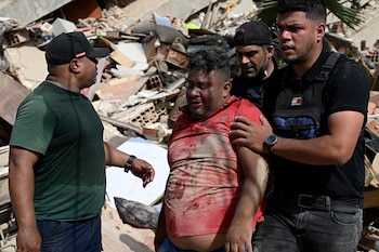 Voluntarios ayudan a un hombre localizado entre los escombros tras el doble terremoto en Caraballeda, La Guaira. (Photo by Federico PARRA / AFP)