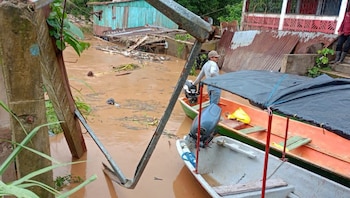 Un hombre se moviliza en lancha frente a viviendas dañadas y escombros tras el desbordamiento de un río, en una comunidad afectada por las inundaciones recientes en Nicaragua.