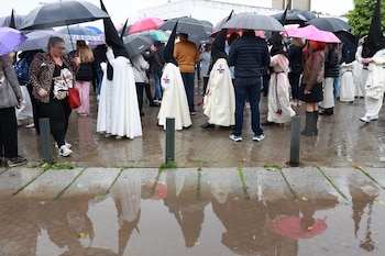 Nazarenos de la Hermandad del Cautivo de San Pablo salen de la Iglesia tras suspenderse por la lluvia su estación de penitencia. (Rocío Ruz / Europa Press)