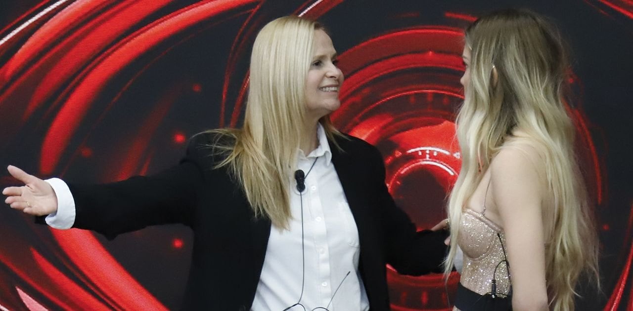 Grecia Colmenares, la icónica actriz de telenovelas, sonríe mientras interactúa con otra mujer en el vibrante escenario del programa Grande Fratello.