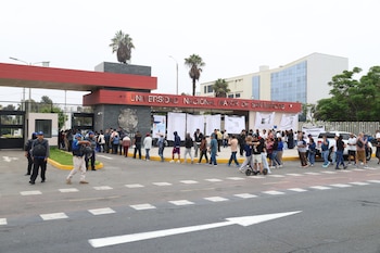 Vista exterior de la entrada principal de la Universidad Nacional Mayor de San Marcos con una multitud de personas formando filas y carteles informativos