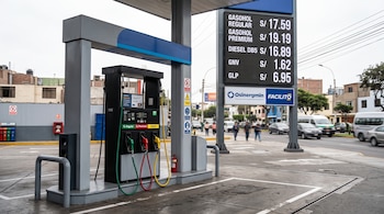 Un surtidor de combustible junto a una pantalla digital con precios y carteles de Osinergmin y Facilito en una calle.