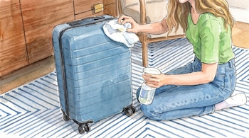 Ilustración de una mujer arrodillada en el suelo con camiseta verde y pantalones vaqueros azules limpiando una maleta azul con un paño y un spray.