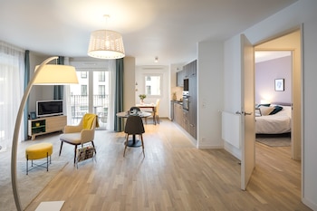 Interior de apartamento con sala, comedor, cocina, balcón, dormitorio, muebles, lámparas, televisión y puerta abierta