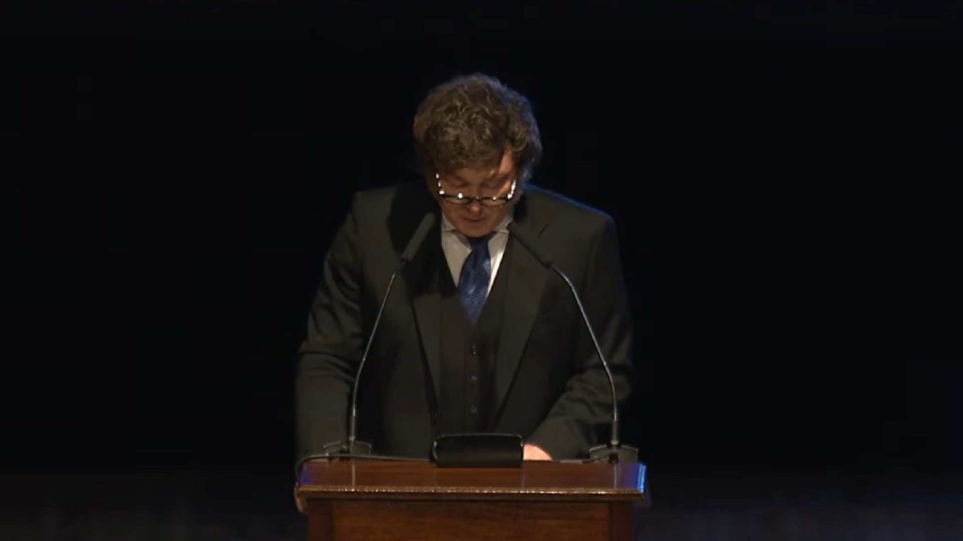 El presidente Javier Milei en el podio durante un homenaje al Rebe de Lubavitch, mostrando respeto por la figura religiosa