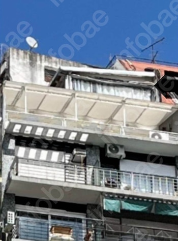 Fachada de un edificio de departamentos con balcones, toldos, unidades de aire acondicionado, una antena parabólica y el cielo azul