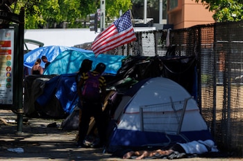 An American flag flutters over the tents of homeless people living along a sidewalk in Los Angeles, California, U.S., June 24, 2024. REUTERS/Mike Bake