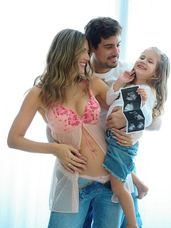 Stephanie Demner, embarazada y sonriente, junto a Guido Pella abrazando a su hija, quien muestra orgullosa la ecografía del futuro bebé