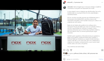 Hombre joven sonriente con una pala de pádel, una mochila y hojas de papel sobre una mesa, con un banner de NOX y una cancha de pádel de fondo