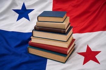 Una pila de varios libros colocada en el centro sobre la bandera desplegada de Panamá.