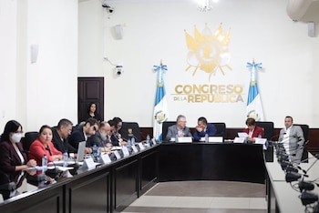 Personas sentadas ante micrófonos en una mesa en forma de herradura, bajo el emblema del Congreso de la República y banderas de Guatemala