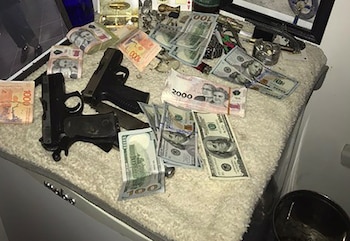 Dos pistolas negras y fajos de billetes de cien dólares y pesos argentinos de 1000 y 2000 descansan sobre una superficie de tela blanca y peluda
