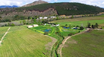 Vista aérea de terrenos agrícolas verdes, tanques circulares, estanques de agua, caminos de tierra y colinas al fondo