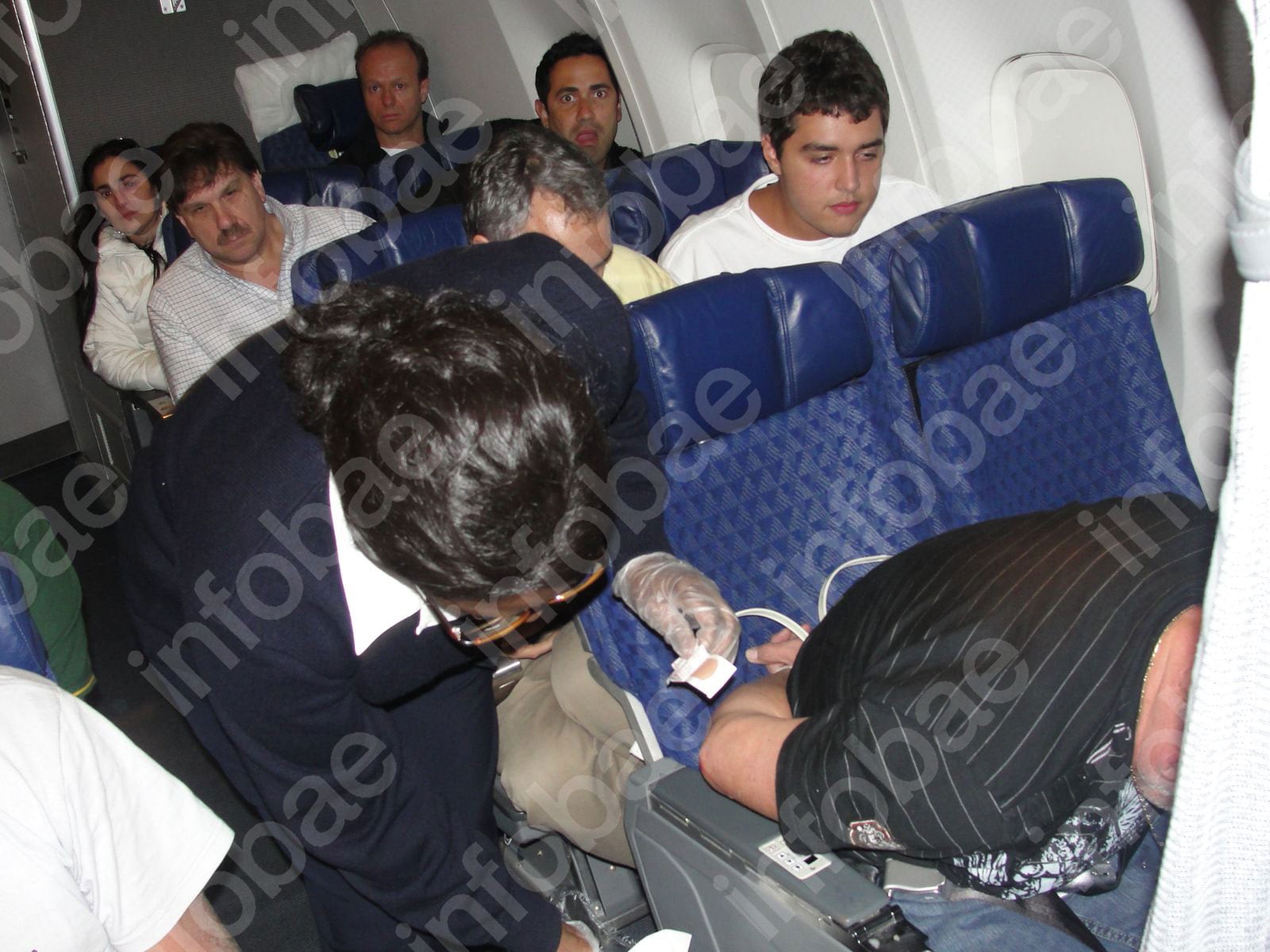 Michael Isabelle con los precintos en las muñecas y una azafata colocándole una curita.