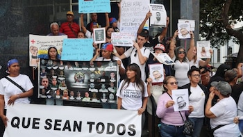 Un grupo de personas sostiene carteles, pancartas con fotografías y una pancarta principal con la frase Que sean todos frente a un edificio