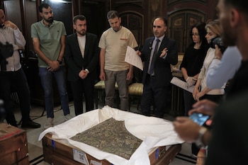 Ayman Nabou, deputy director-general of Antiquities and Museums, speaks as museum employees and officials gather around an antiquity returned from France at the National Museum in Damascus, Syria, Wednesday, July 8, 2026.(AP Photo/Ghaith Alsayed)