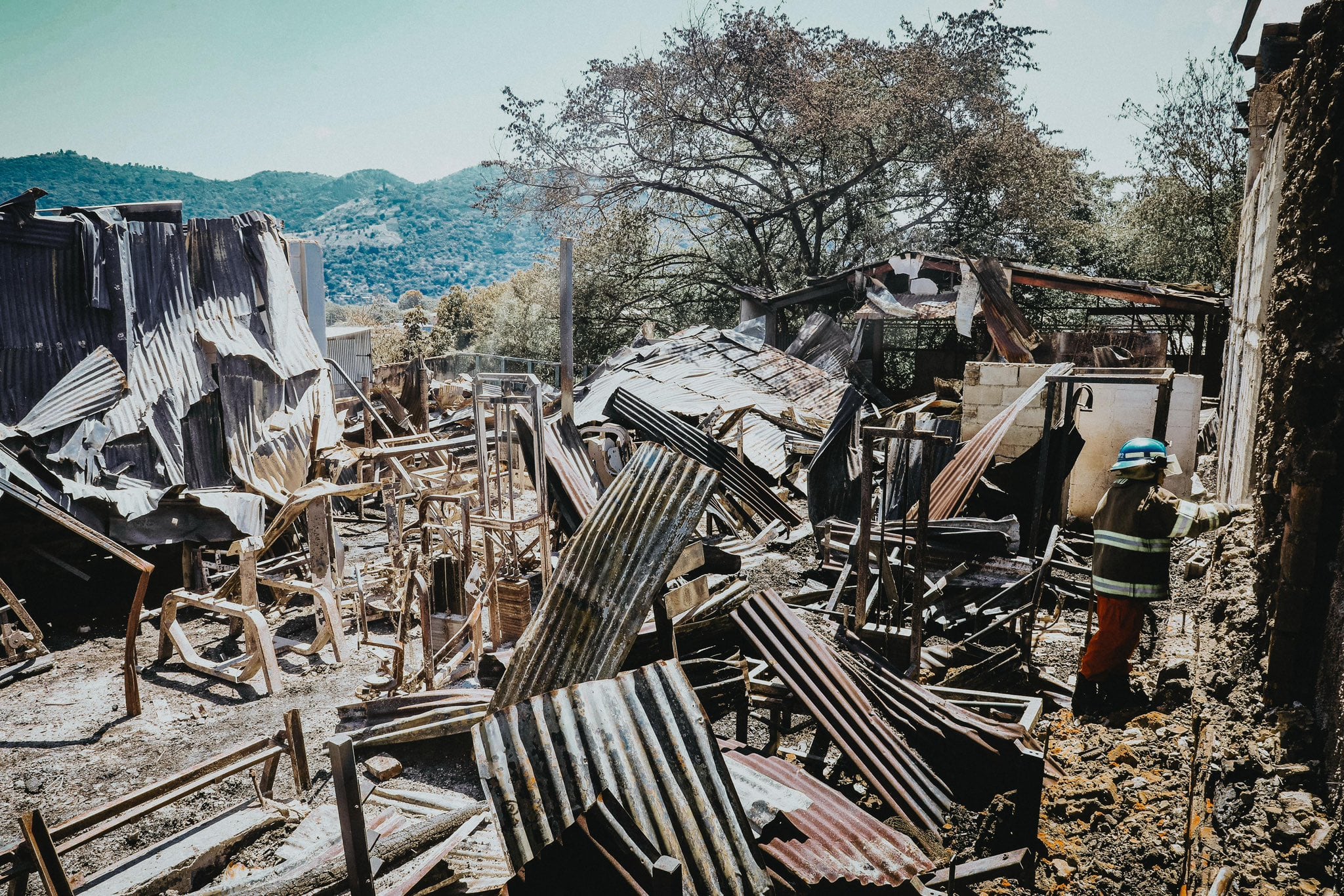 Un bombero inspecciona los restos calcinados de estructuras de lámina y madera tras el incendio en el centro de San Salvador, mientras continúan las labores de remoción entre los escombros (Foto cortesía Secretaría de Prensa).