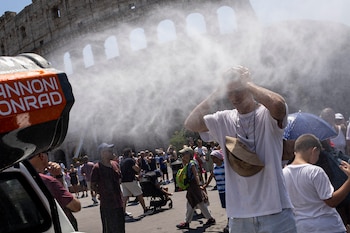Los visitantes se refrescan entre nebulizadores de agua instalados cerca del Coliseo en Roma, 26 de junio de 2026. (EFE/MASSIMO PERCOSSI)