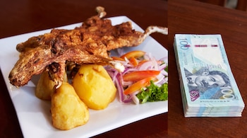 Un plato blanco contiene un cuy frito, tres papas y ensalada de lechuga, cebolla roja y tomate. A su lado, un fajo de billetes de cien soles.
